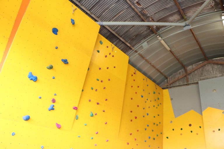 a large yellow climbing wall in a shed.